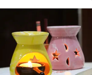 Ceramic star moon essential oil burner detail shot showing warm candle light and cute cutouts.