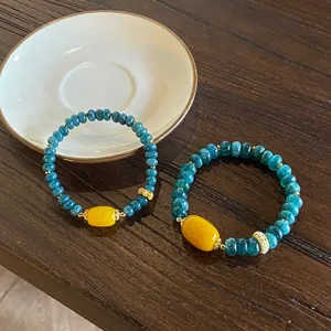 Blue stone abacus bead bracelet detail, featuring yellow agate central bead and gold spacers.