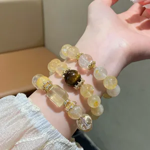 Detail view of natural yellow crystal beaded bracelet stack, chic retro design with gold charms.