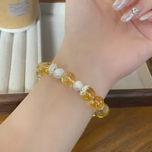 Vue détaillée de l'élégant bracelet de perles en cristal jaune et perles blanches au poignet.