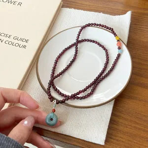 Gros plan détail du bracelet multitorus en grenat naturel avec pendentif boucle de jade.