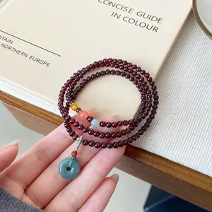 Gros plan sur le bracelet en grenat à tours multiples avec boucle en jade et perles délicates.