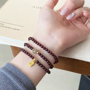 Bracelet de grenat multicouche style chinois avec perle de jade et charm de bénédiction dorée.