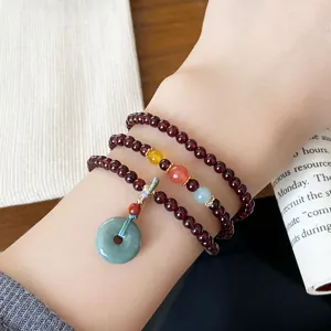 Détail du bracelet multibrins en grenat avec perles de pierres précieuses et pendentif.
