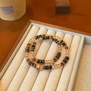 Détail de bracelets superposés en œil de tigre et perles de cristal sur plateau de présentation.