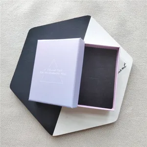 Gros plan sur un coffret cadeau de bijoux violet clair avec insert en mousse noire et triangle.
