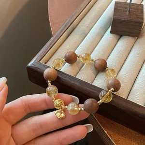 Detailed view of Chinese style lucky citrine and sandalwood beaded bracelet with lock charm.