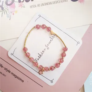 Gros plan sur le détail du bracelet de perles en cristal craquelé, pendentif cœur et étoile.
