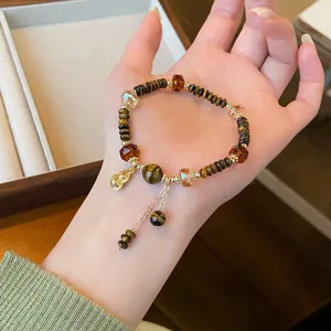 Vue détail d'un bracelet de perles en pierre naturelle œil de tigre rétro avec pendentif gourde.