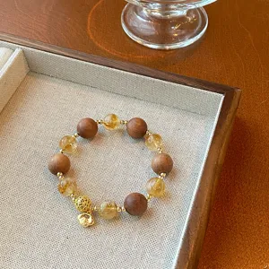 Detailed close-up shot of Chinese style citrine sandalwood beaded bracelet with gold lock charm.