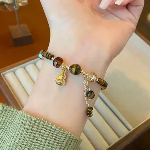 Vue detaillee du bracelet de perles en pierre naturelle d'oeil de tigre avec pendentif gourde.
