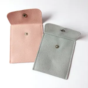 Gros plan de poches de rangement à bijoux en suède doux avec boutons-pression en rose et gris.