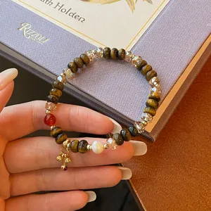 Gros plan détail de bracelet de perles vintage avec œil de tigre, cristaux et pendentif gourde.