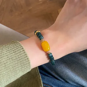 Detailed view of the retro Chinese style green and yellow agate bead bracelet on wrist.