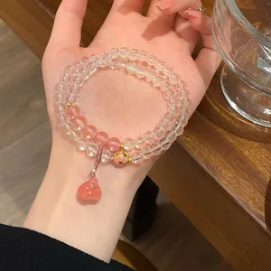 Detailed shot of multi-layer crystal and pink gemstone bracelet with delicate gold charm.