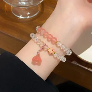 Detailed closeup of double layer crystal bead bracelets worn on wrist with floral charm.
