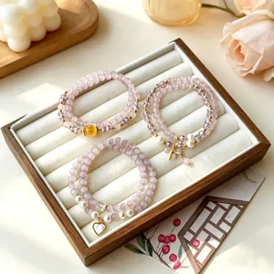 Joli bracelet double en perles mauves avec pendentif nœud et cœur pour femmes.