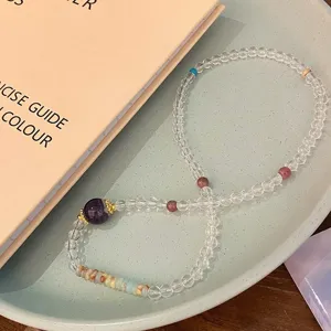 Joli bracelet de perles en cristal naturel coloré avec pierre violette et détails dorés.