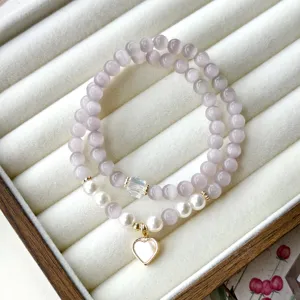 Gros plan détaillé du bracelet à double rang en pierre d'œil de chat violette avec perles.