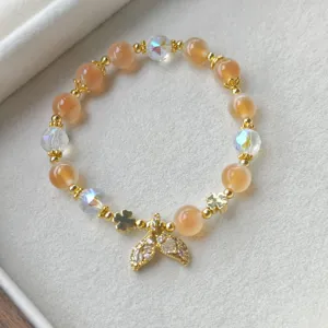 Détail en gros plan d'un bracelet de perles d'agate douce avec cristaux et pendentif queue.