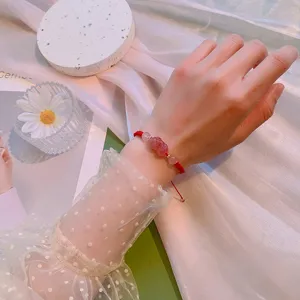Gros plan detaille du bracelet en corde rouge fait main avec cristal de fraise et perle.
