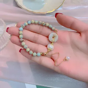 Close-up detail of the vintage national style jade bead bracelet with pearl and donut pendant.