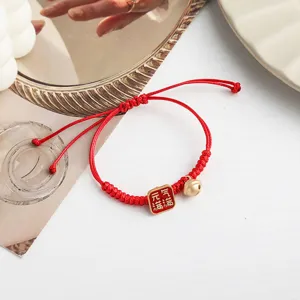 Rotes geflochtenes Seilarmband mit Glocke und chinesischem Glücksanhänger als Geschenk.