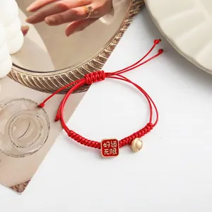 Rotes geflochtenes Armband mit quadratischem Glücksanhänger und Glocke für das Neujahrsfest.