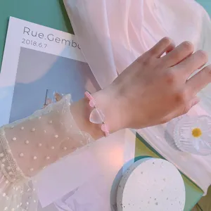 Gros-plan sur les détails du bracelet tressé en cristal rose, quartz doux au poignet.