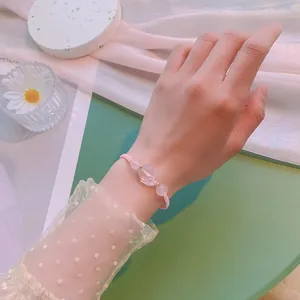 Gros plan d'un bracelet de perles en cristal rose délicat avec cordon tressé rose.