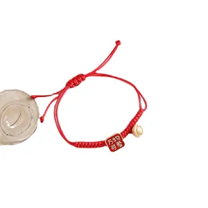 Rotes geflochtenes Armband mit süßem Anhänger und kleiner goldener Glocke, Neujahrsschmuck.