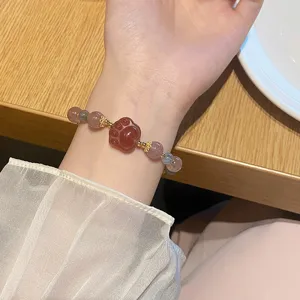 Nahraufnahme eines süßen Erdbeerquarz und Mondstein Pfoten Anhänger Perlenarmbands.