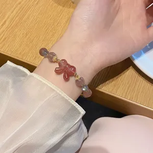 Detailansicht des süßen Erdbeerquarz und Graumondstein Kristallarmbands am schönen Handgelenk.