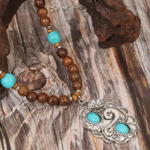 Close-up detail of ethnic vintage necklace with wooden beads, turquoise stones and silver pendant.