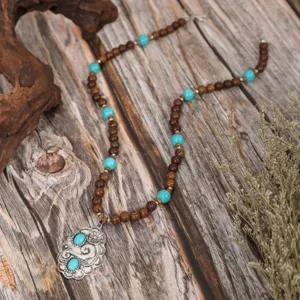 Exquisite vintage ethnic style turquoise and wood bead necklace with ornate silver pendant detail.