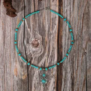 Boho vintage turquoise beaded necklace with carved metal pendant, detailed jewelry view.