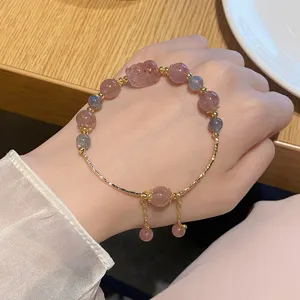 Nahaufnahme Detail eines süßen Erdbeerquarz und Graumondstein Perlenarmbands mit Bärenanhänger.
