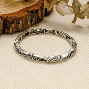 Bracelet élastique en métal argenté style vintage bohème avec sculptures et strass discrets.