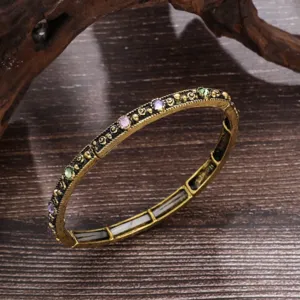Gros plan d'un bracelet extensible vintage bohème avec gravure complexe et strass colorés étincelants.
