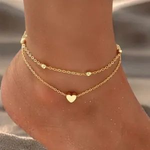 Double layer gold anklet with cute heart pendant and dainty beads for summer beach wear.