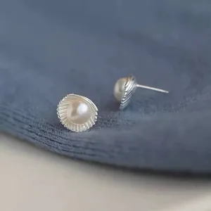 Close-up detail of the exquisite shell pearl stud earrings showing textured metallic design.