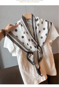 Detail shot of white polka dot silk scarf tied on white tee, showing delicate fabric and style.