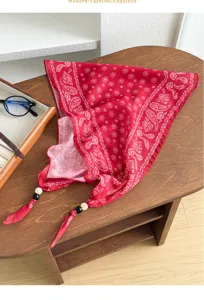 Close-up detail view of a vintage red paisley print bandana scarf with decorative bead ties.