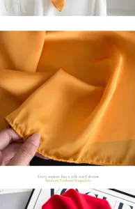 Detailed view of smooth satin silk scarf showing soft orange fabric texture and fine stitching.