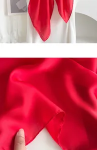 Red silk scarf close up detail texture showing smooth fabric and elegant neckerchief style.