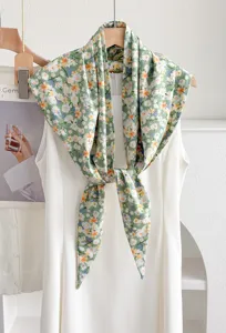 Primo piano dettaglio di foulard triangolare stampa floreale verde su sfondo abito.