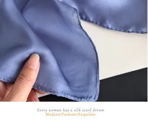 Close-up detail of blue silk scarf texture showing delicate fabric and fine rolled edges.