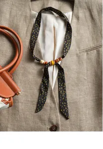 Detail view of vintage abstract print ribbon scarf featuring natural wooden beads, elegant style.