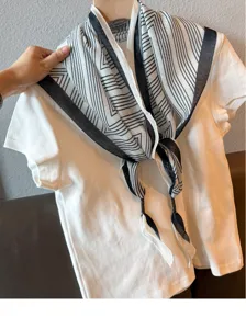 Close-up detail of black and white striped geometric triangle scarf draped on white tee.