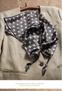 Detailed view of dark brown silk scarf with wavy dot pattern draped elegantly on a textured jacket.